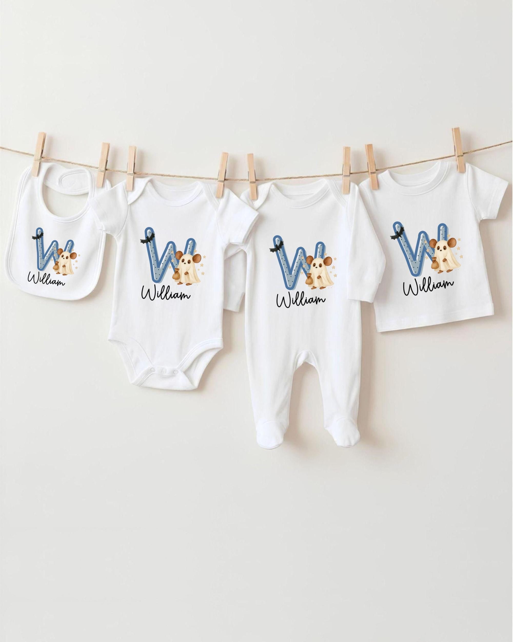 A collection of baby clothes, including onesies and bibs, hanging on a clothesline.