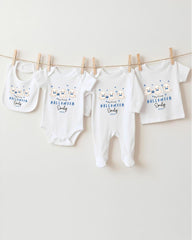 A row of four white baby clothes with Halloween-themed designs hanging on a clothesline.