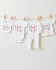 A row of four white baby clothes with the name "Hannah" printed on them, hanging on a clothesline.