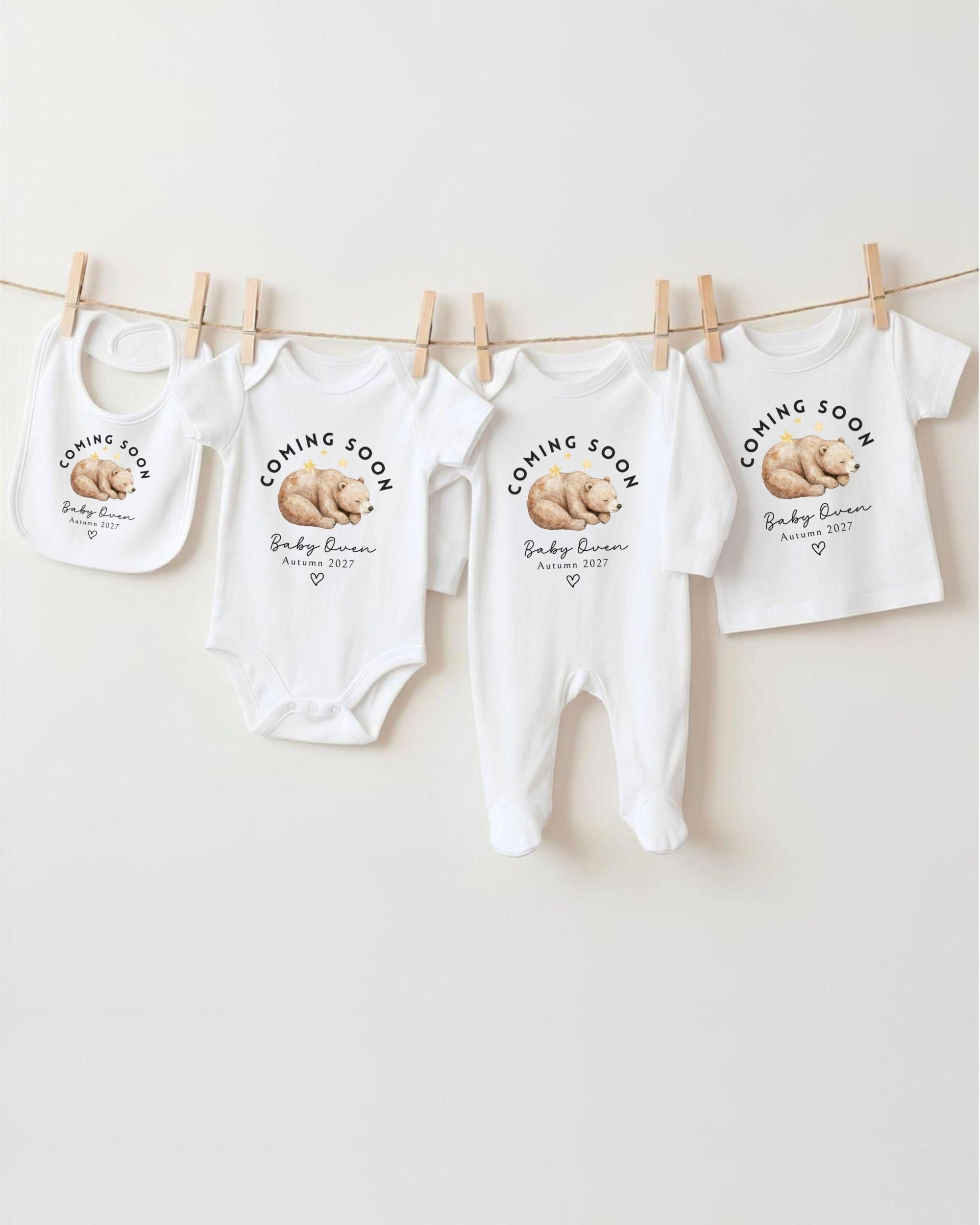 A row of white baby clothes with the text "Coming Soon Baby Girl" printed on them, along with a bear image.