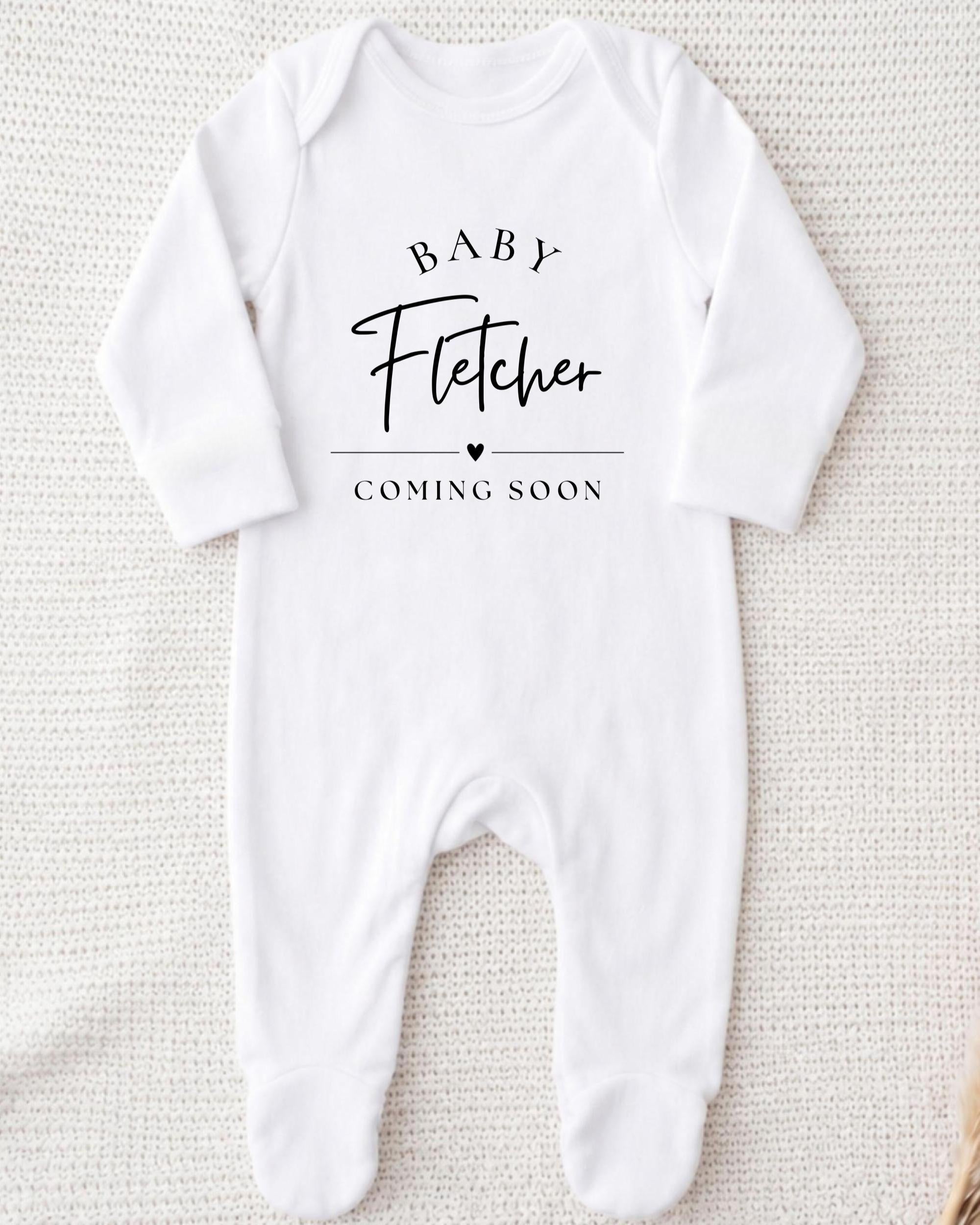 A white onesie with the text "BABY Fetcher COMING SOON" printed on it.