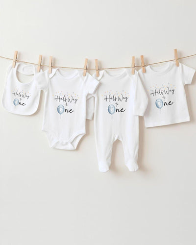 A row of four white baby clothes, including onesies and pajamas, hanging on a clothesline.