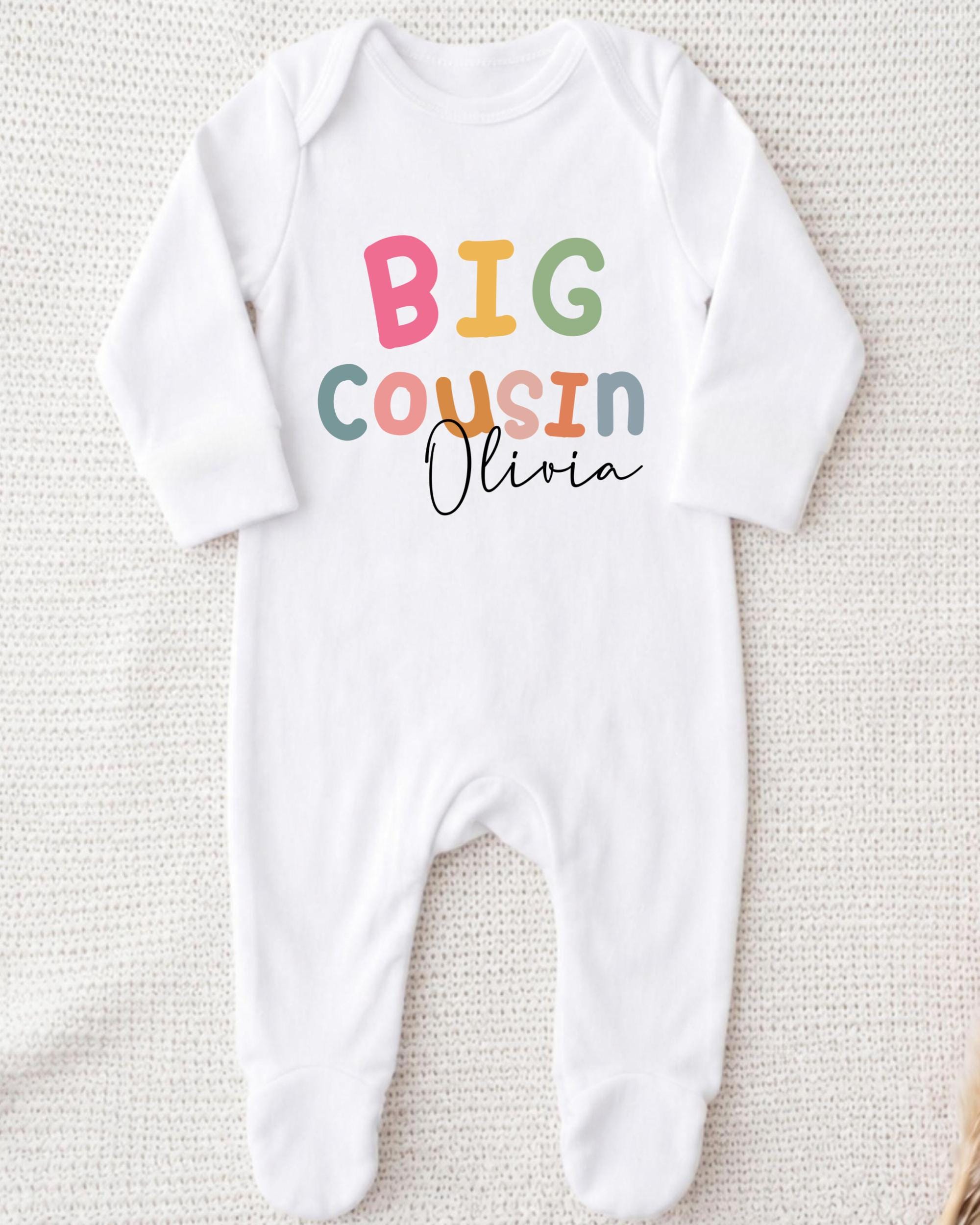A white onesie with the text "BIG COUSIN Olivia" printed on it.