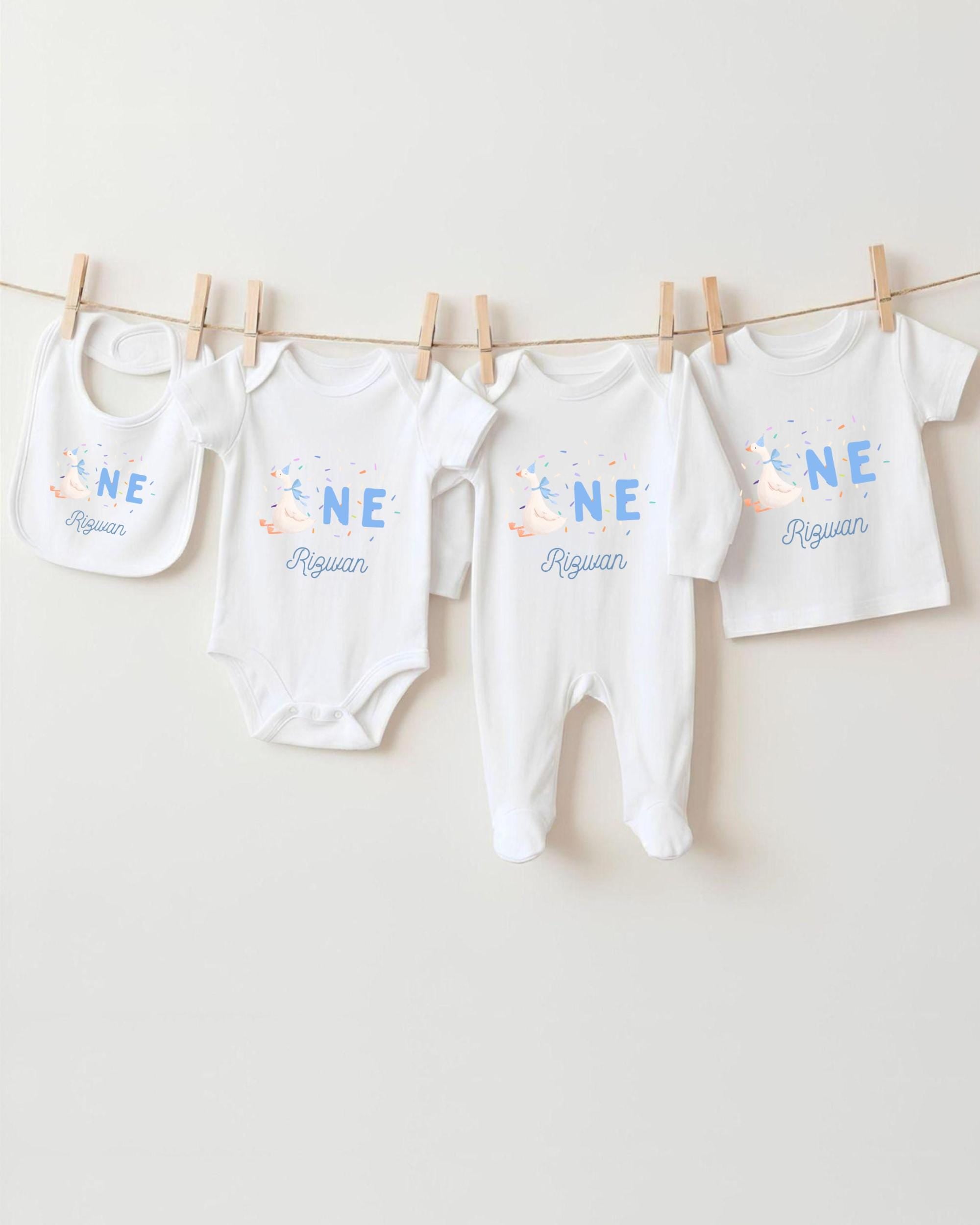 A collection of white baby clothes, including onesies and bibs, hanging on a clothesline.