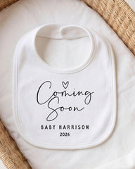 A white bib with the text "Coming Soon" printed on it, placed on a white cloth.