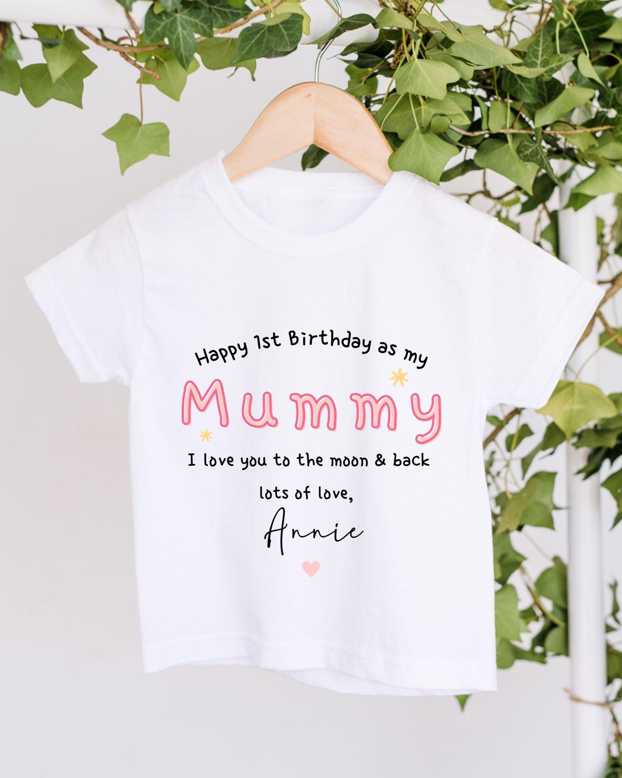 A white t-shirt with a personalized message printed on it, hanging on a wooden hanger.