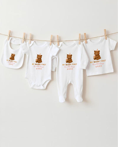 A row of white baby clothes with brown bear designs, each with a personalized message printed on it.