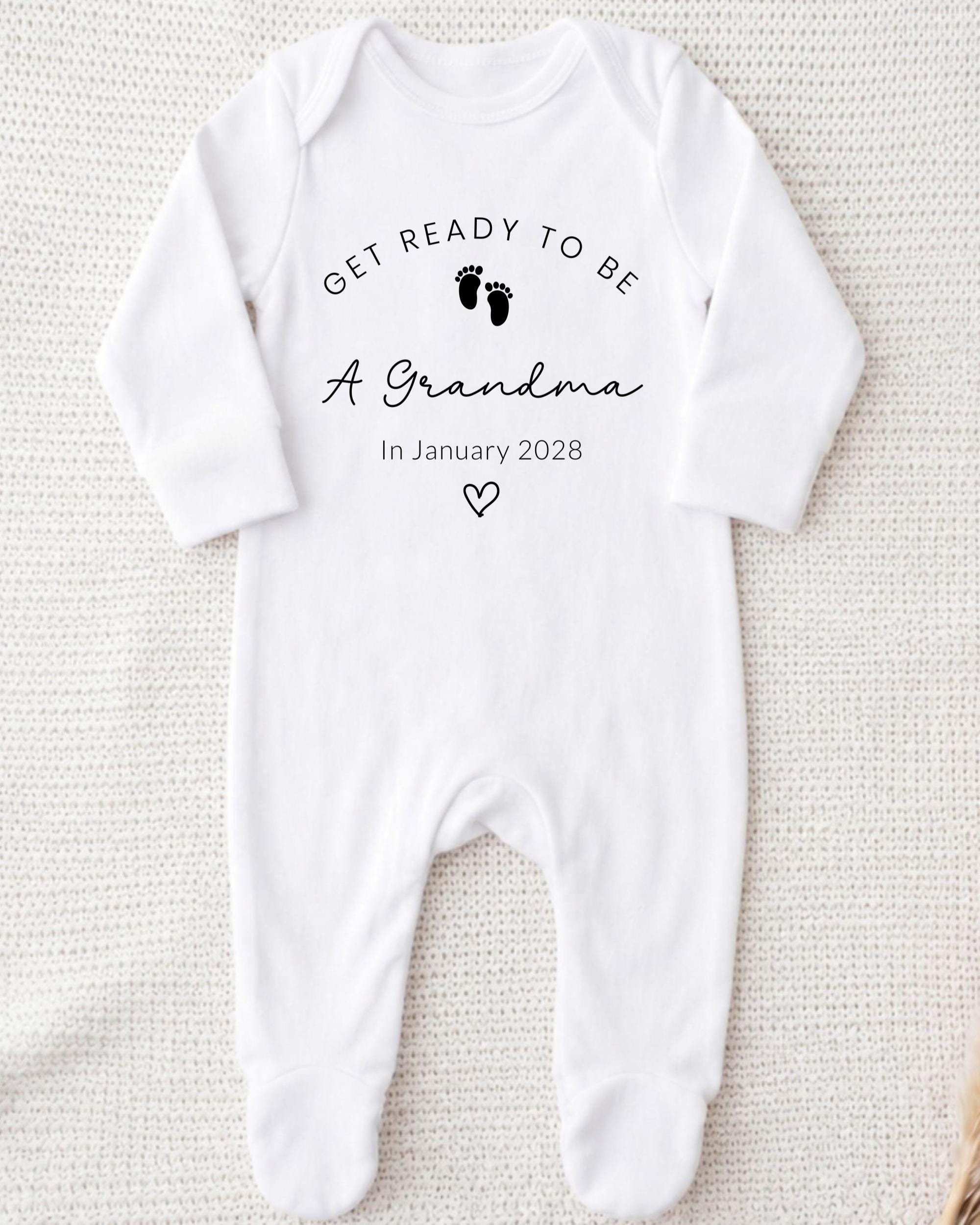 A white onesie with the text "Get ready to be a Grandma In January 2028" printed on it.