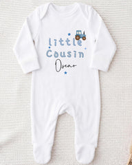 A white onesie with blue text and a tractor graphic printed on it.