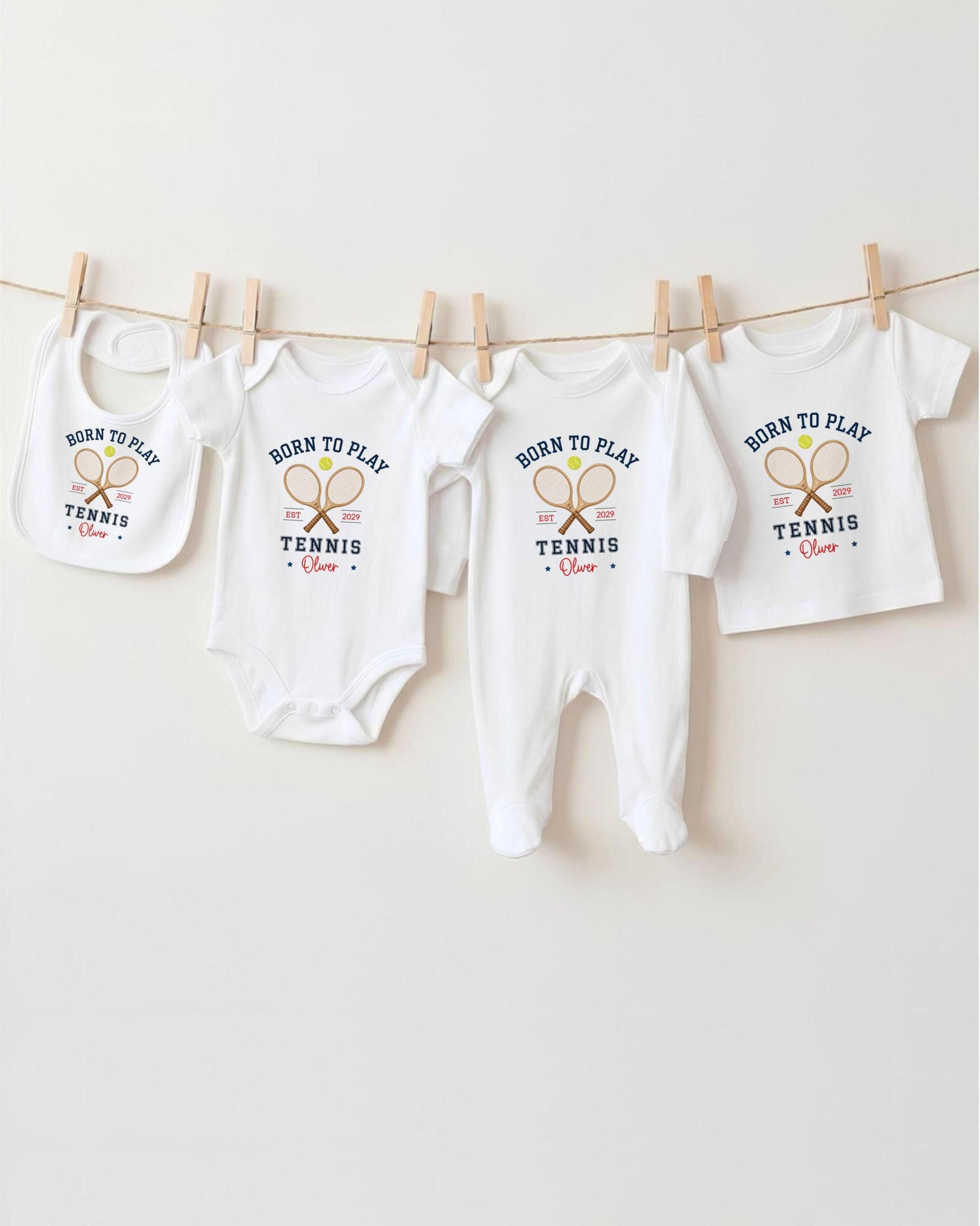 A row of white baby clothes with the text "Born to play tennis" printed on them, along with tennis rackets.