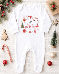 A white onesie with a Christmas-themed design, surrounded by various Christmas decorations and gifts, including a small Christmas tree, ornaments, and a candy cane.