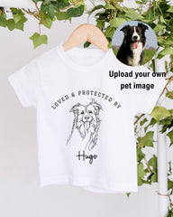 A white t-shirt with a black and white dog illustration and the text "LOVED & PROTECTED BY Hugo" printed on it.