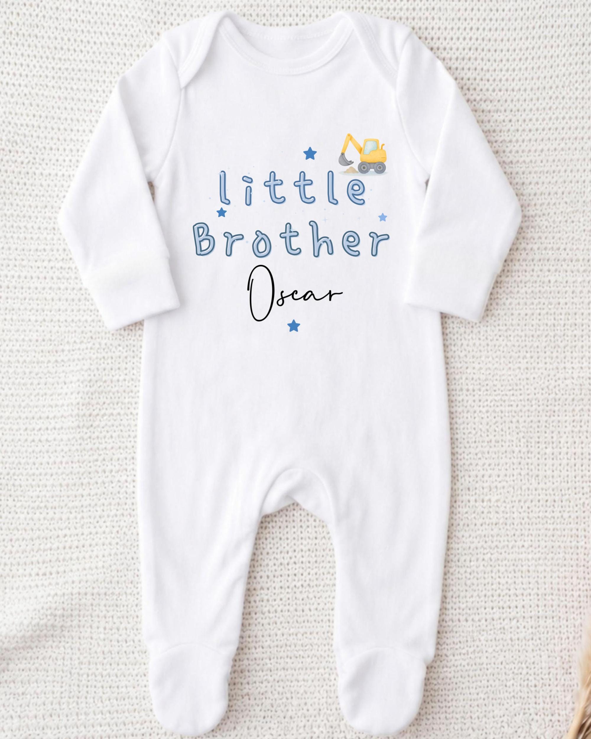 A white onesie with blue text and a construction vehicle graphic, indicating it is a baby onesie with a personalized message.