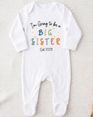 A white onesie with text that says "I'm going to be a big sister" printed on it.