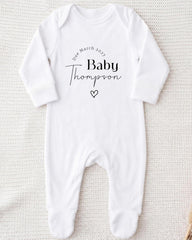 A white onesie with the text "Due March 2027 Baby Thompson" printed on it.