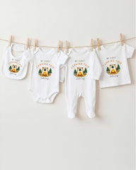 A collection of four white baby clothes, including onesies and bibs, hanging on a clothesline.