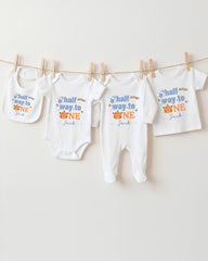A collection of baby clothes, including onesies and bibs, hanging on a clothesline.