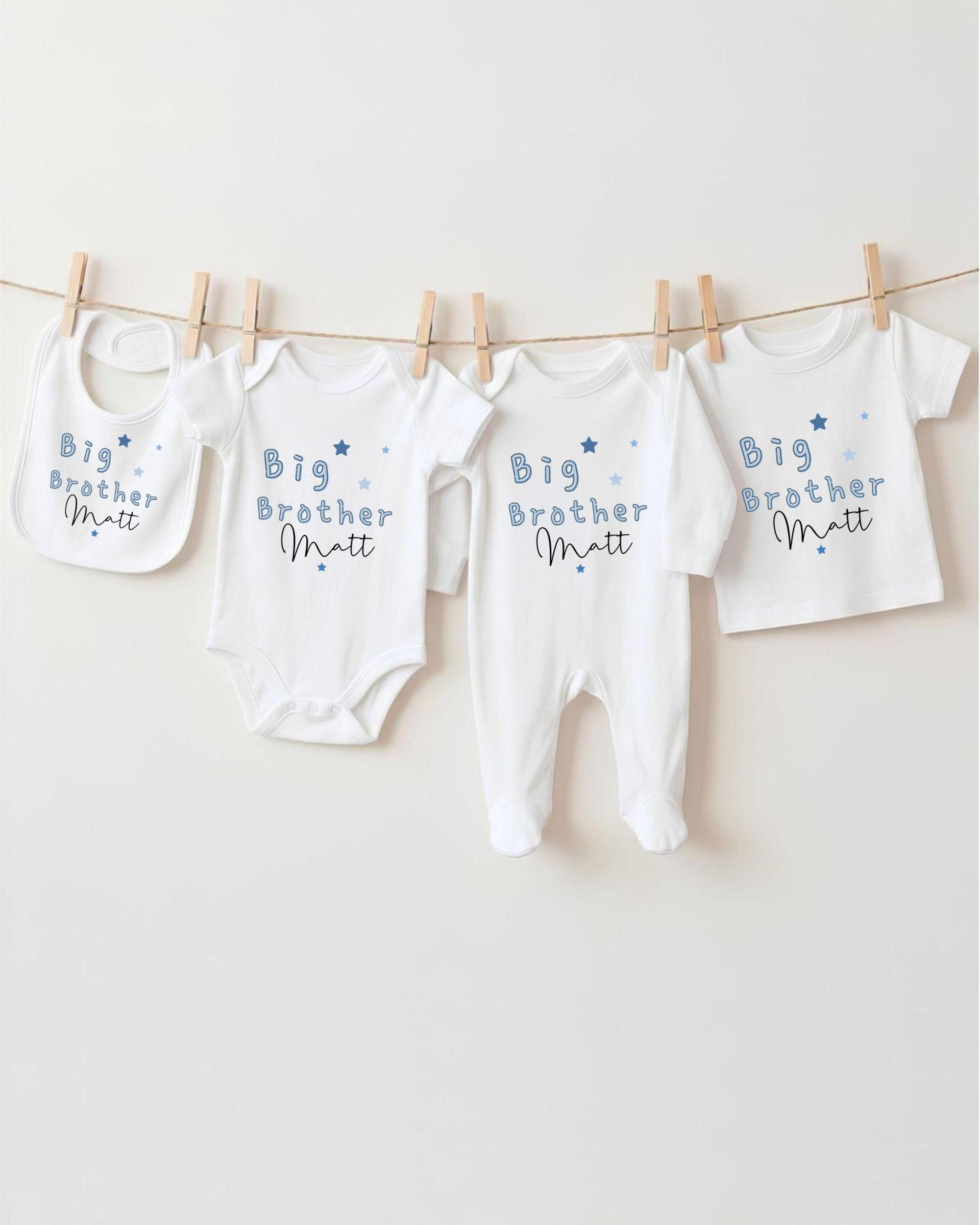 A row of four white baby clothes with the text "Big Brother Matt" printed on them, hanging on a clothesline.