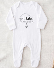 A white onesie with the text "Due March 2027 Baby Thompson" printed on it.
