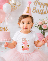 A young girl wearing a birthday hat and a white t-shirt with a personalized number 1 design is posing for a birthday photo.