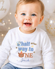 A smiling baby boy wearing a white shirt with a birthday message printed on it.