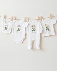 A collection of white baby clothes, including onesies and bibs, hanging on a clothesline.