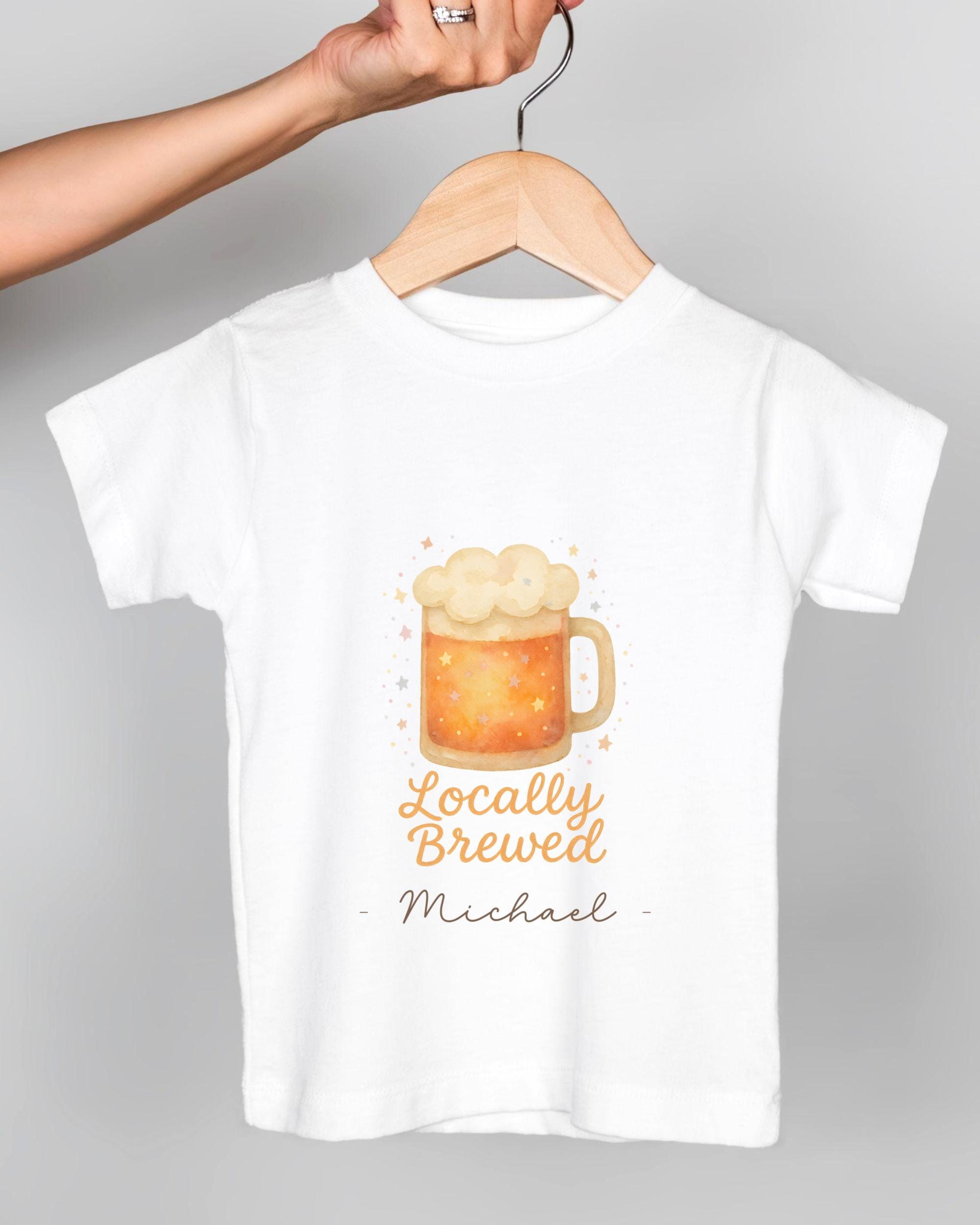 A white t-shirt with a graphic of a mug of beer and the text "Locally Brewed Michael" printed on it.