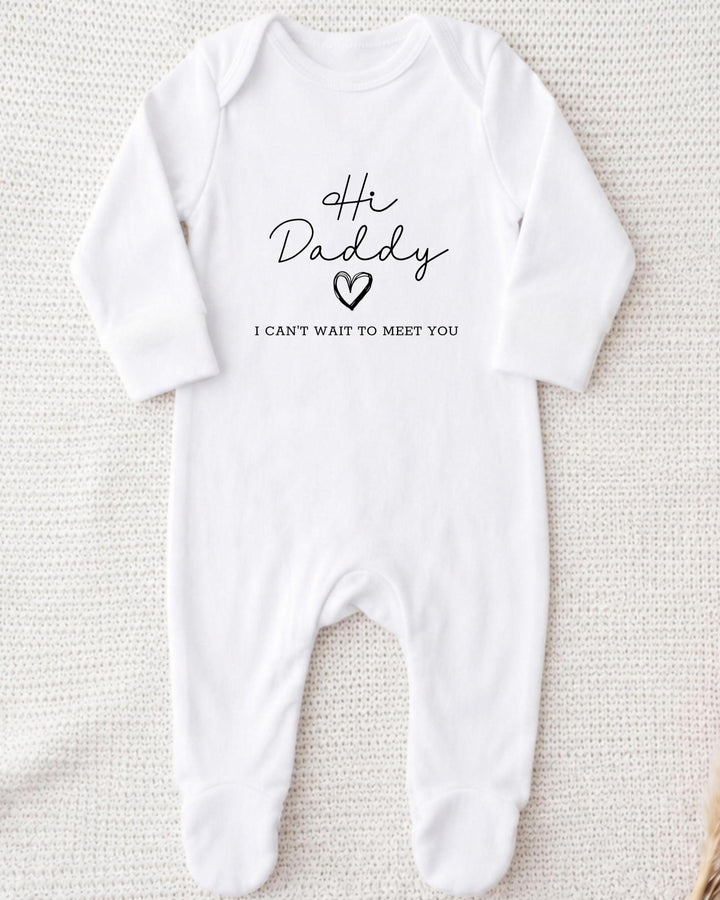 White Baby Grow with black script 'Hi Daddy', an outlined heart and small block 'I can't wait to meet you' lettering.