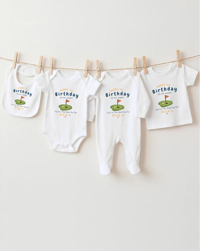 A collection of four white baby clothes, including onesies and bibs, hanging on a clothesline.