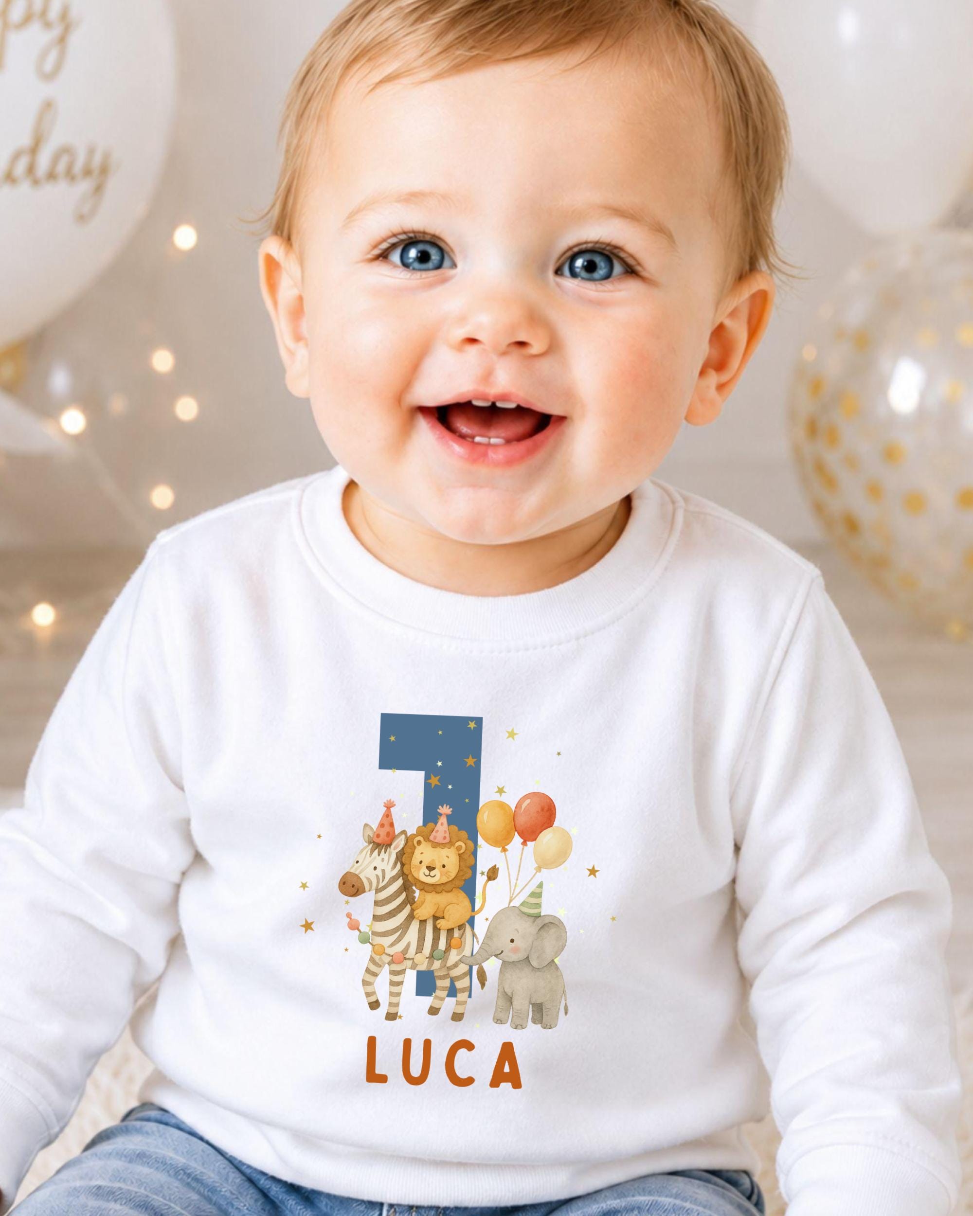 A smiling baby boy wearing a white shirt with a personalized number 1 and animal-themed design.