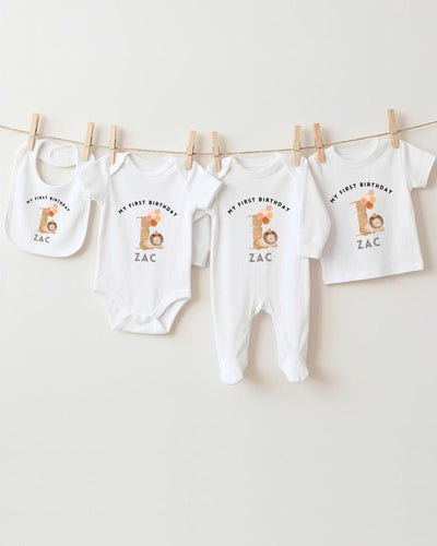 A collection of white baby clothes, including bodysuits and bibs, hanging on a clothesline.