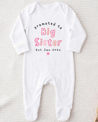A white onesie with text printed on it, which appears to be a promotional item for a baby sister.