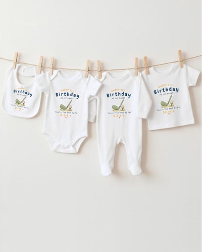 A row of four white baby clothes hanging on a clothesline, each with a birthday message printed on it.