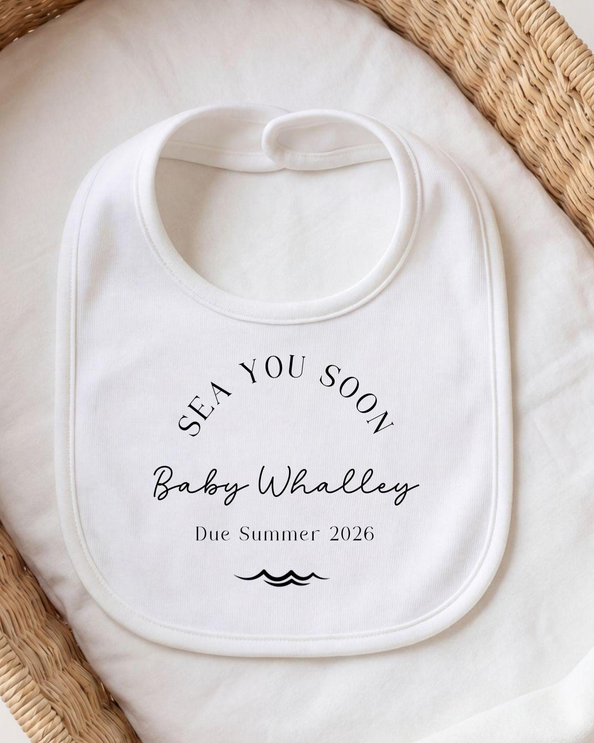 A white bib with text printed on it, placed on a white cloth.