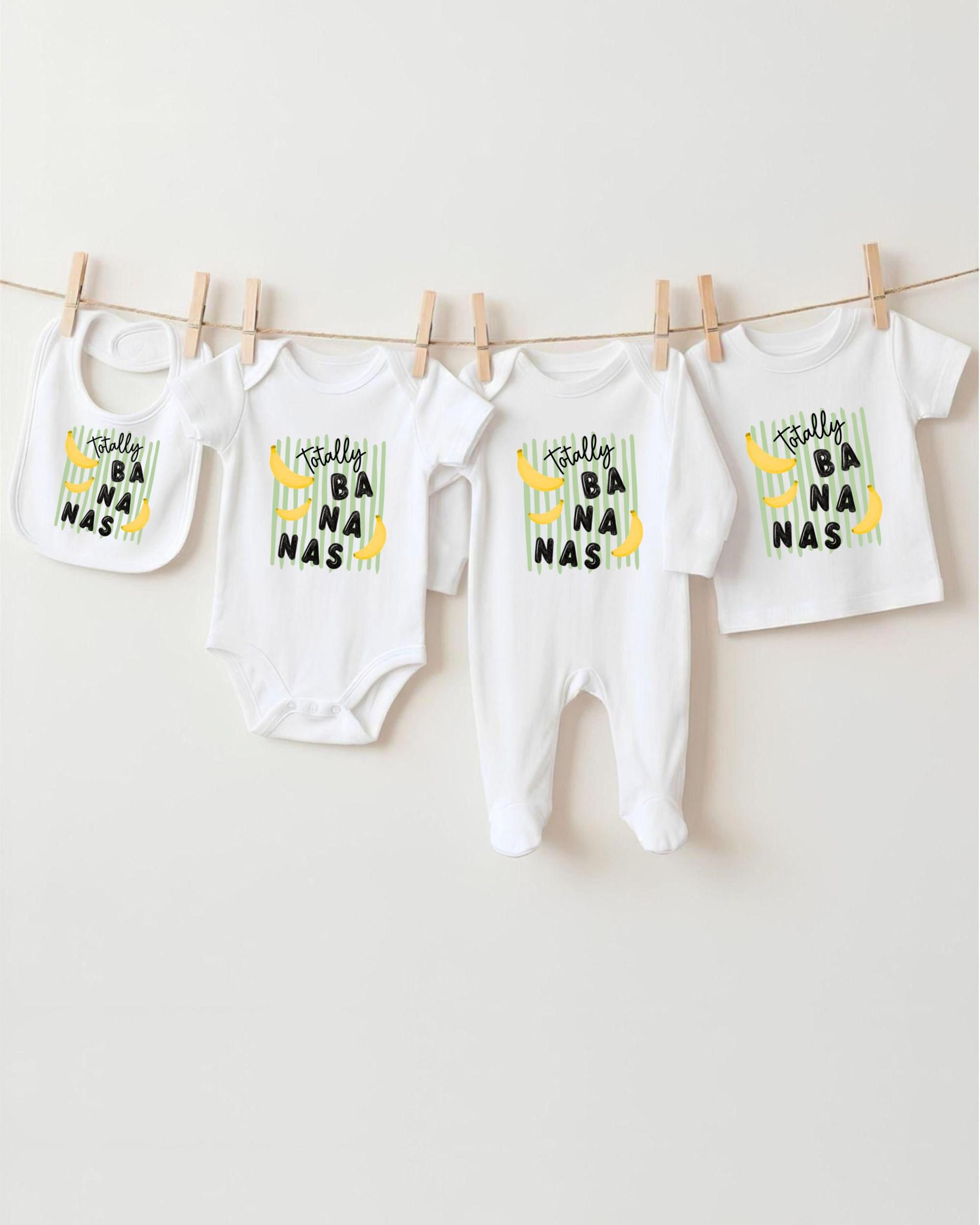 A collection of baby clothes, including onesies and bibs, hanging on a clothesline.