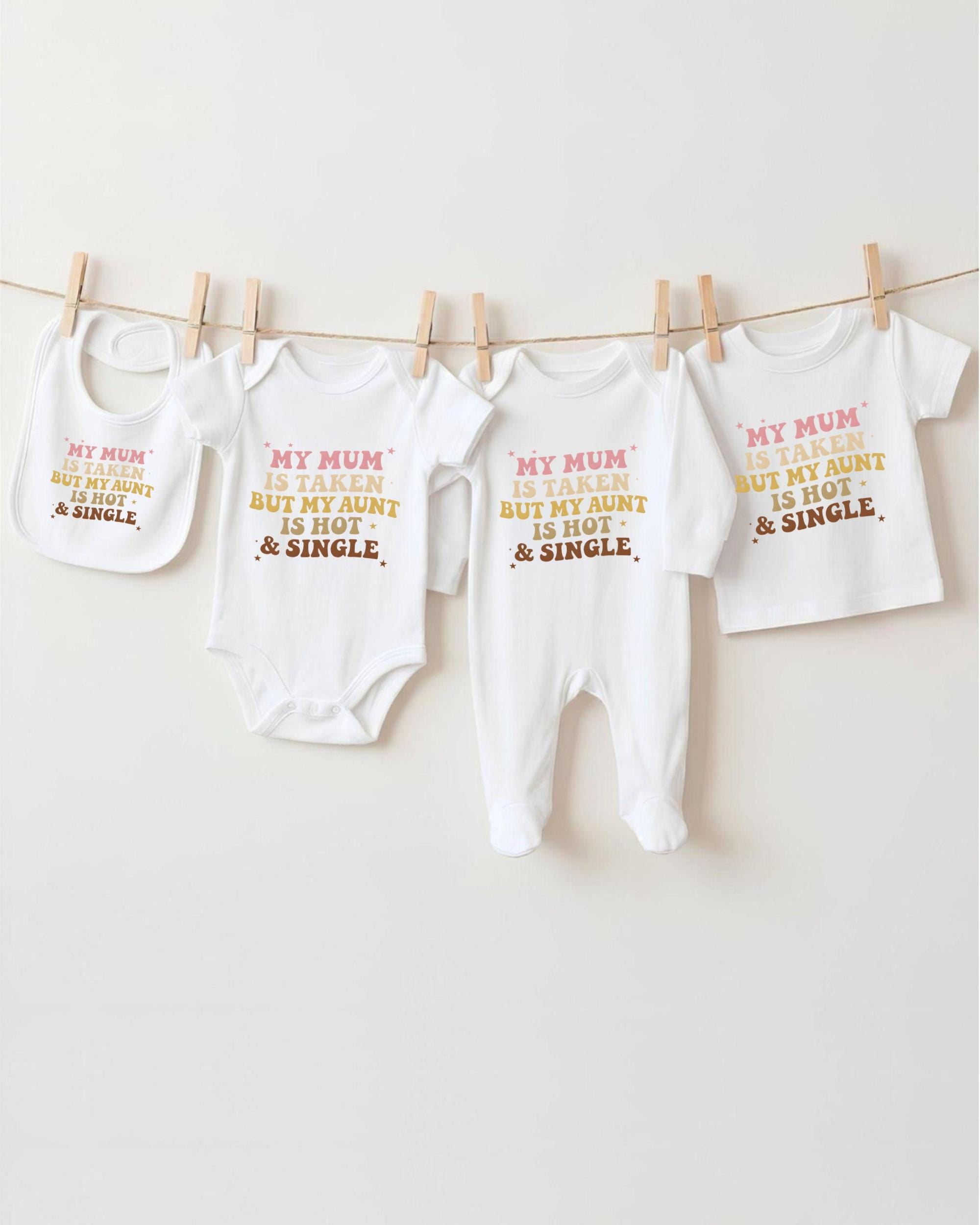 a collection of baby clothes hanging on a clothesline, with each piece featuring a humorous text printed on it.