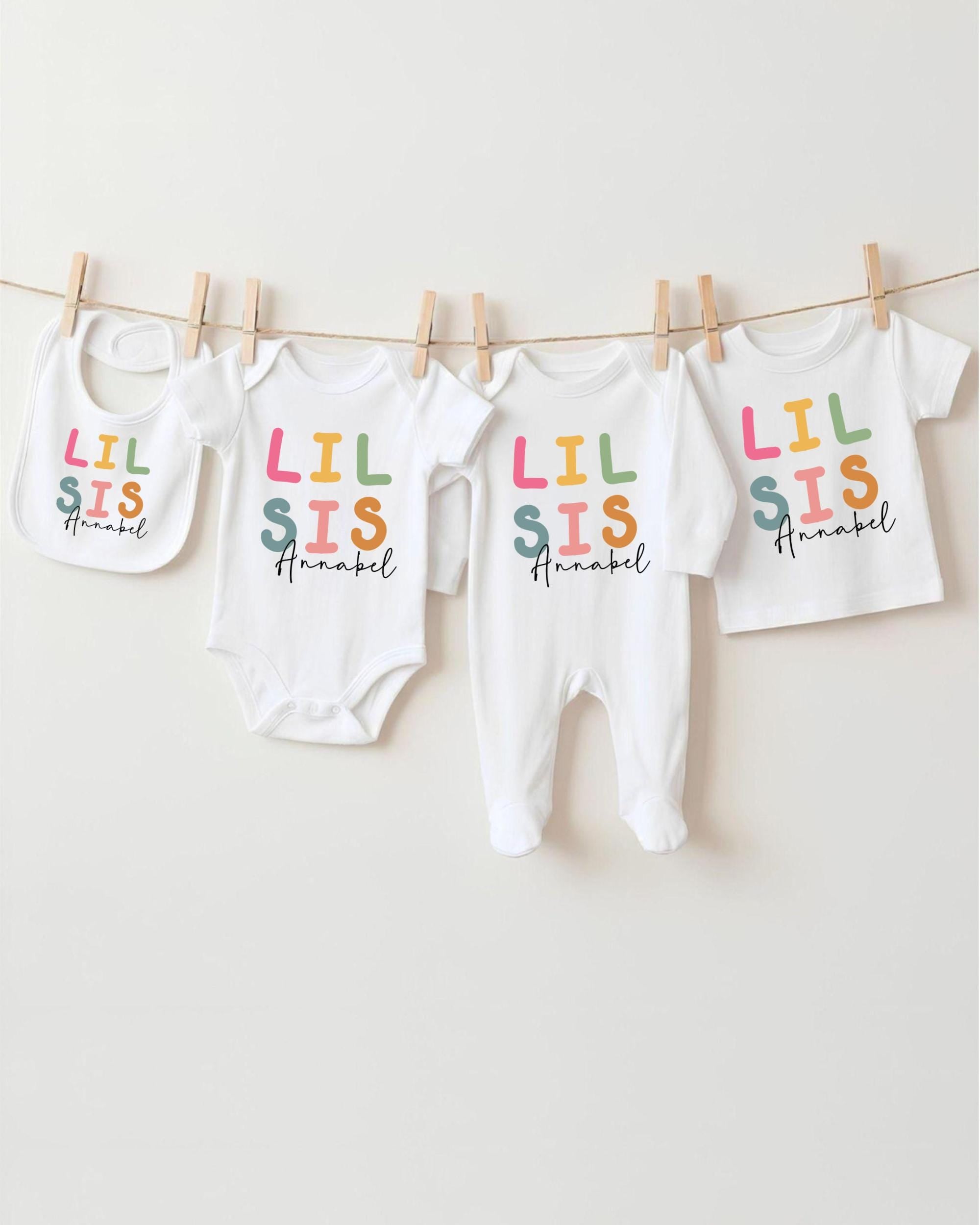 A collection of baby clothes, including onesies and bibs, hanging on a clothesline.