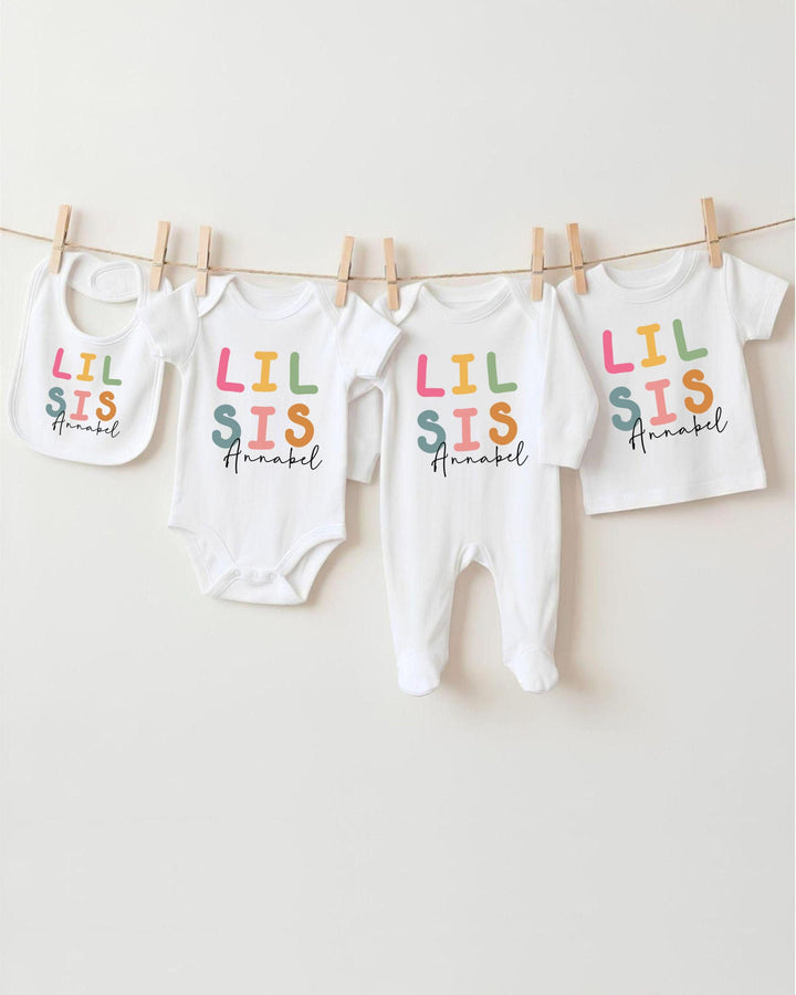 A collection of baby clothes, including bodysuits and bibs, hanging on a clothesline.