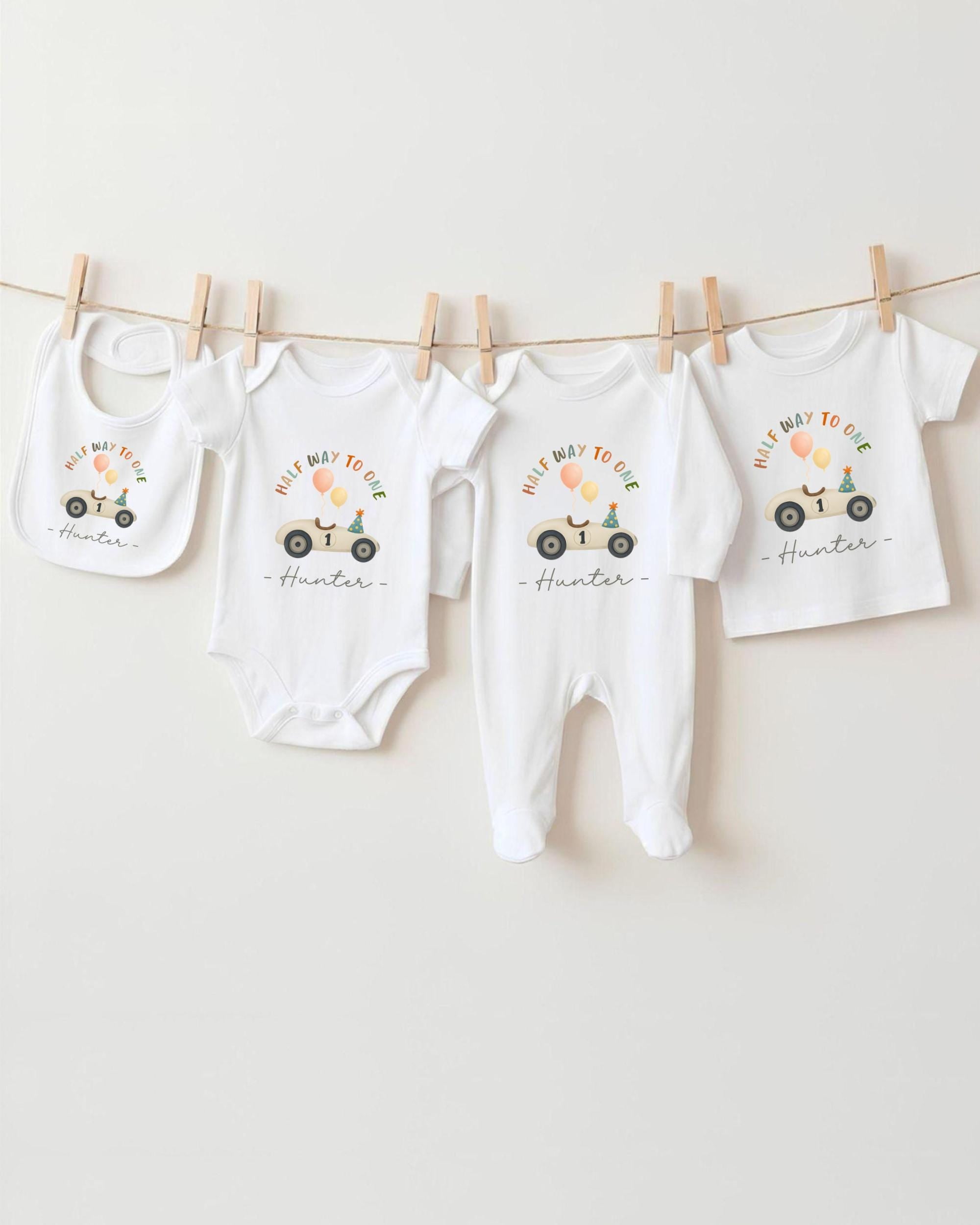 A collection of white baby clothes, including onesies and bibs, hanging on a clothesline.