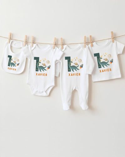 A collection of baby clothes, including bodysuits and bibs, hanging on a clothesline.
