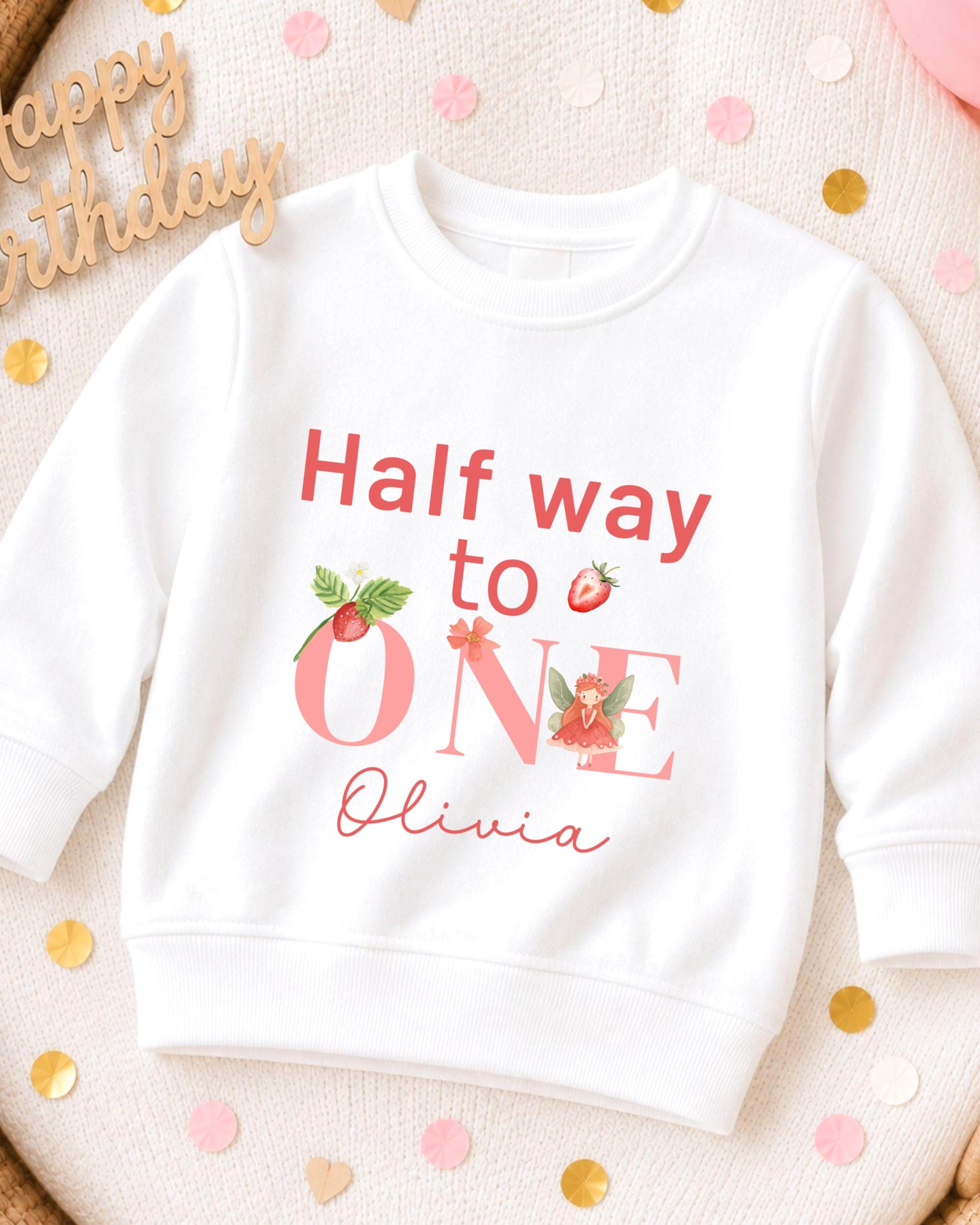 A white sweatshirt with a personalized message printed on it, placed on a surface with confetti.