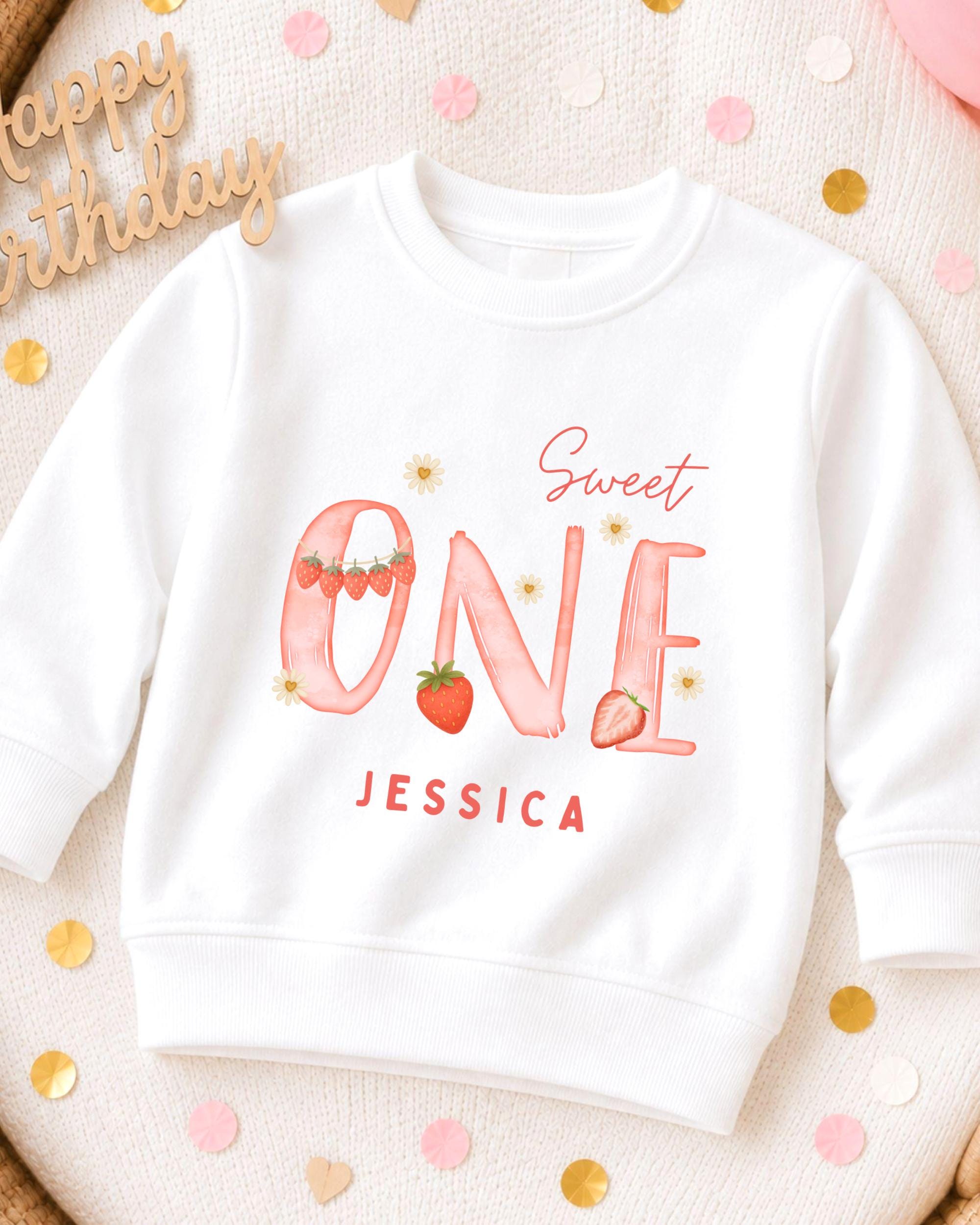 A white sweatshirt with a personalized design on it, featuring the text "Sweet One" and the name " Jessica".