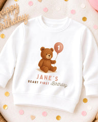 A white sweatshirt with a teddy bear and a balloon, along with the text "JANE'S BIRTHDAY" printed on it.