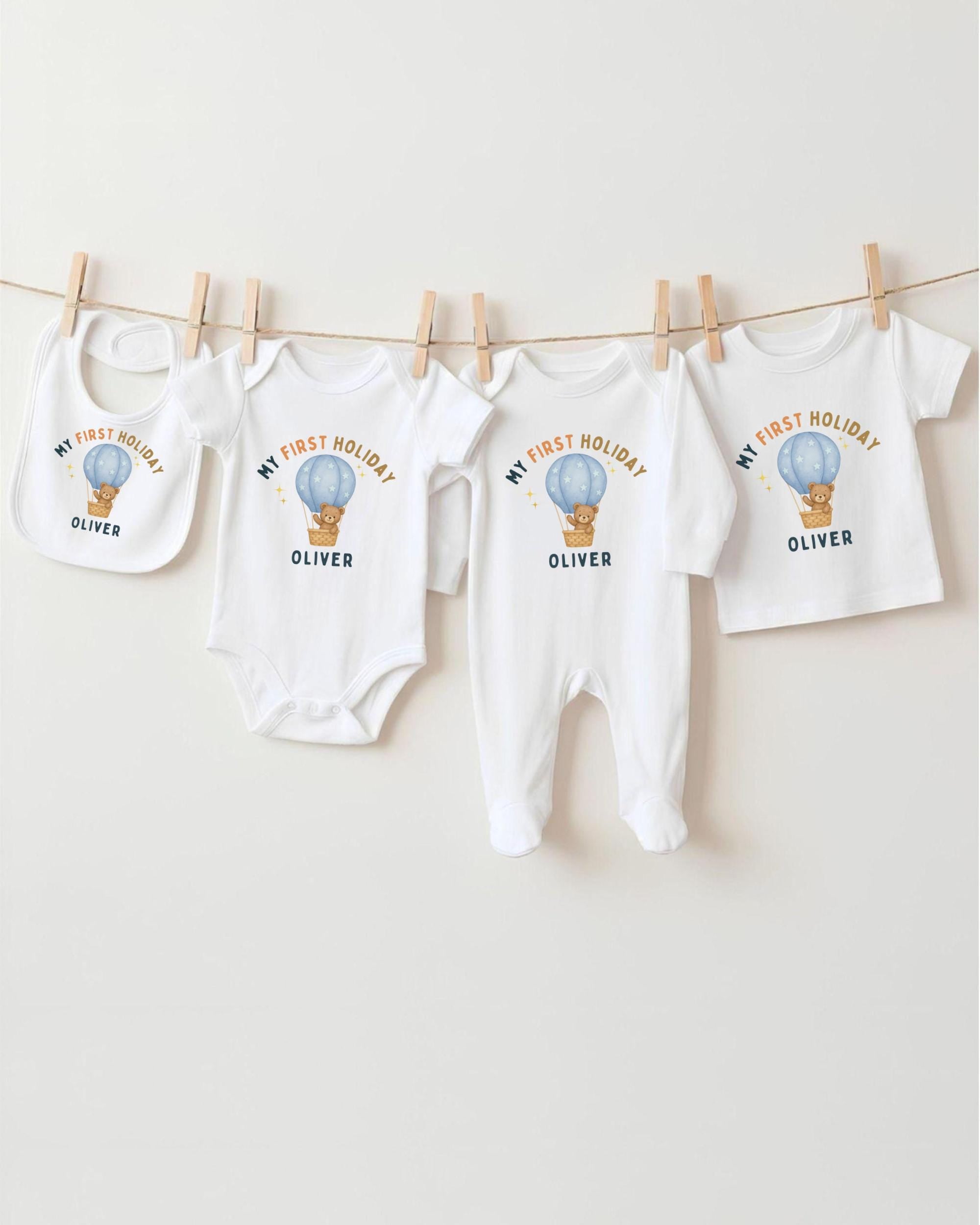 A row of four white baby clothes with a hot air balloon design, each with a different name printed on it.