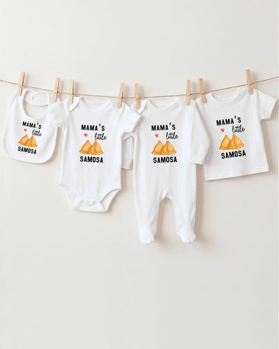 A row of four white baby clothes with the text "MAMA'S LITTLE SAMOSA" printed on them, hanging on a clothesline.