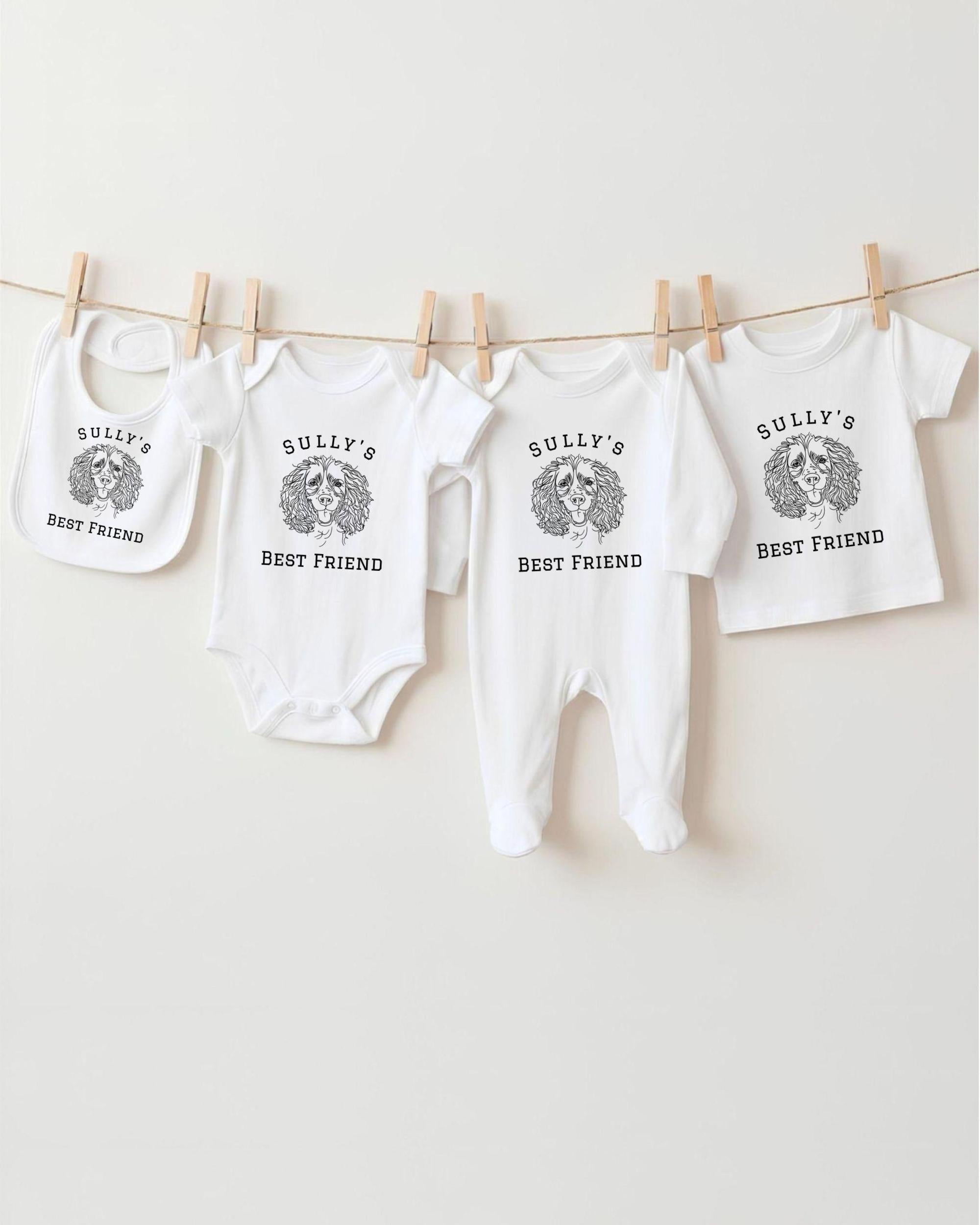 A row of white baby clothes with the text "Sully's BEST FRIEND" printed on them, along with a bib featuring the same text.