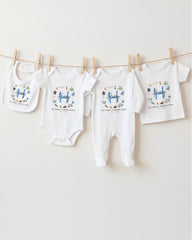 A row of four white baby clothes, including onesies and bibs, hanging on a clothesline.
