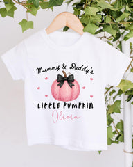 A white t-shirt with a graphic design featuring a pink pumpkin and the text "Mummy & Daddy's LITTLE PUMPKIN Olivia" printed on it.
