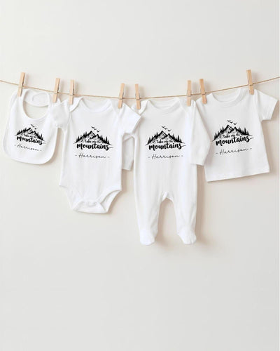A row of four white baby clothes with a mountain design, hanging on a clothesline.