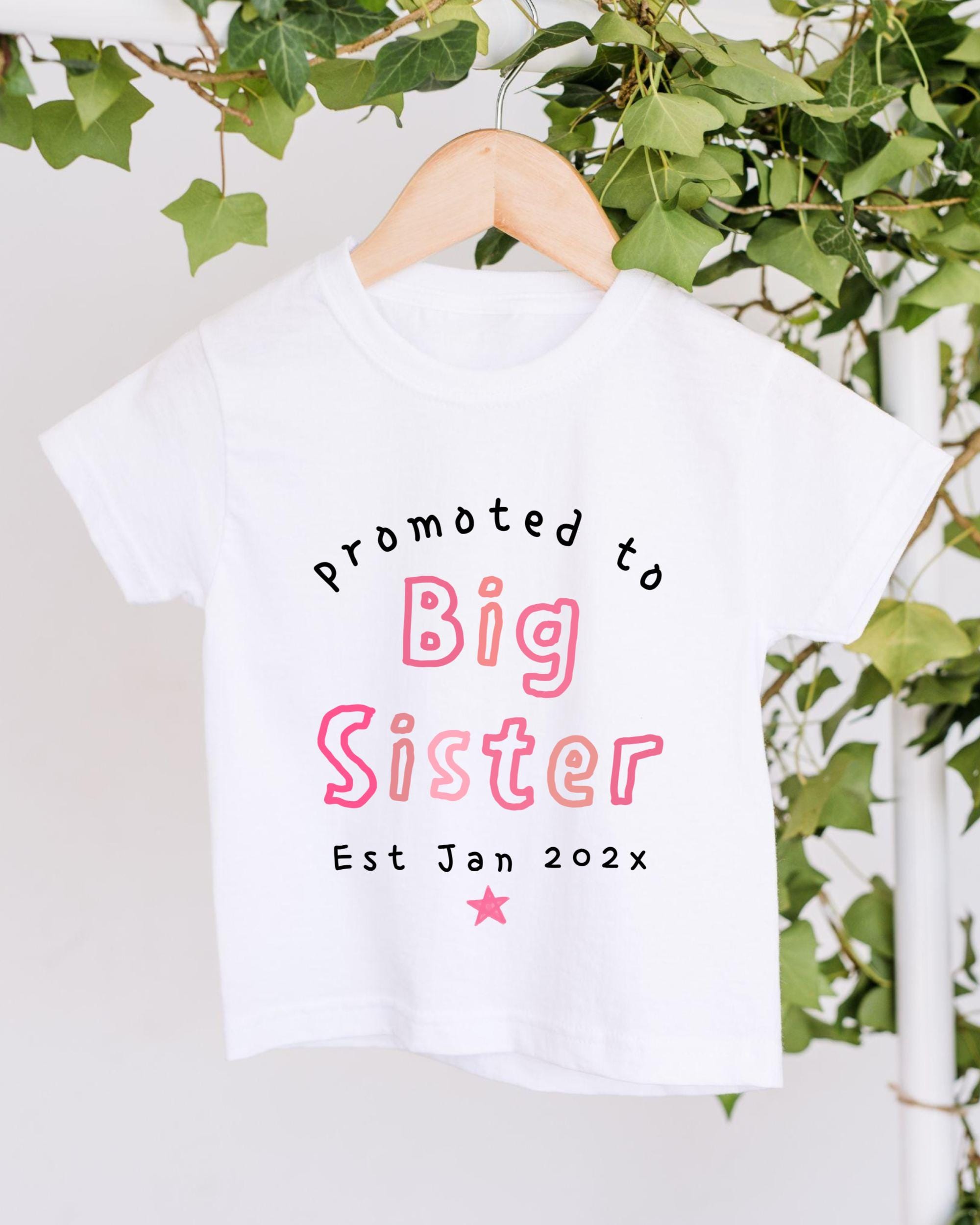 A white t-shirt with text that reads "Promoted to Big Sister Est Jan 202x" printed on it.